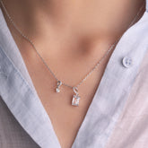 Fine jewellery, silver jewellery, hypoallergenic, tarnish-free, Front view close-up of a silver Necklace with 2 crystal pendants worn by a person wearing a light blue shirt.